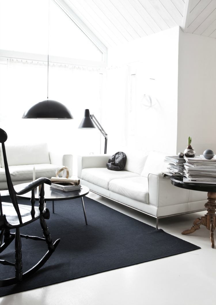 فرش مشکی در اتاق و مبلمان سفید و صندلی راحتی